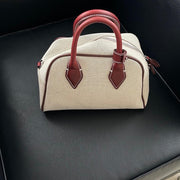 dome-shaped handbag with a cream canvas body and dark brown leather handles