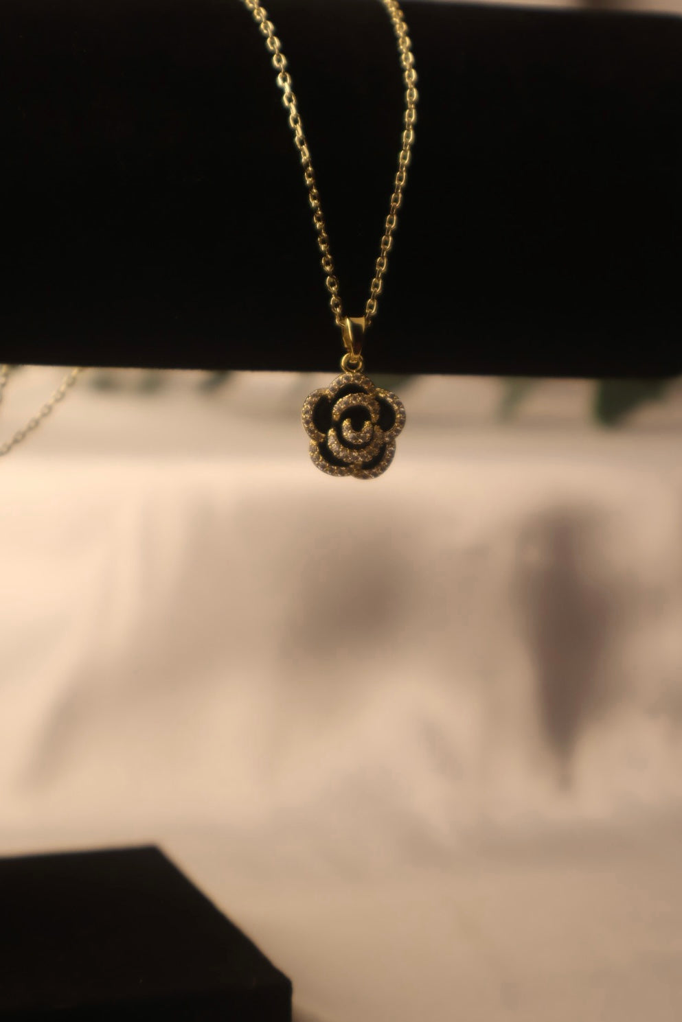 gold chain with black flower pendent
