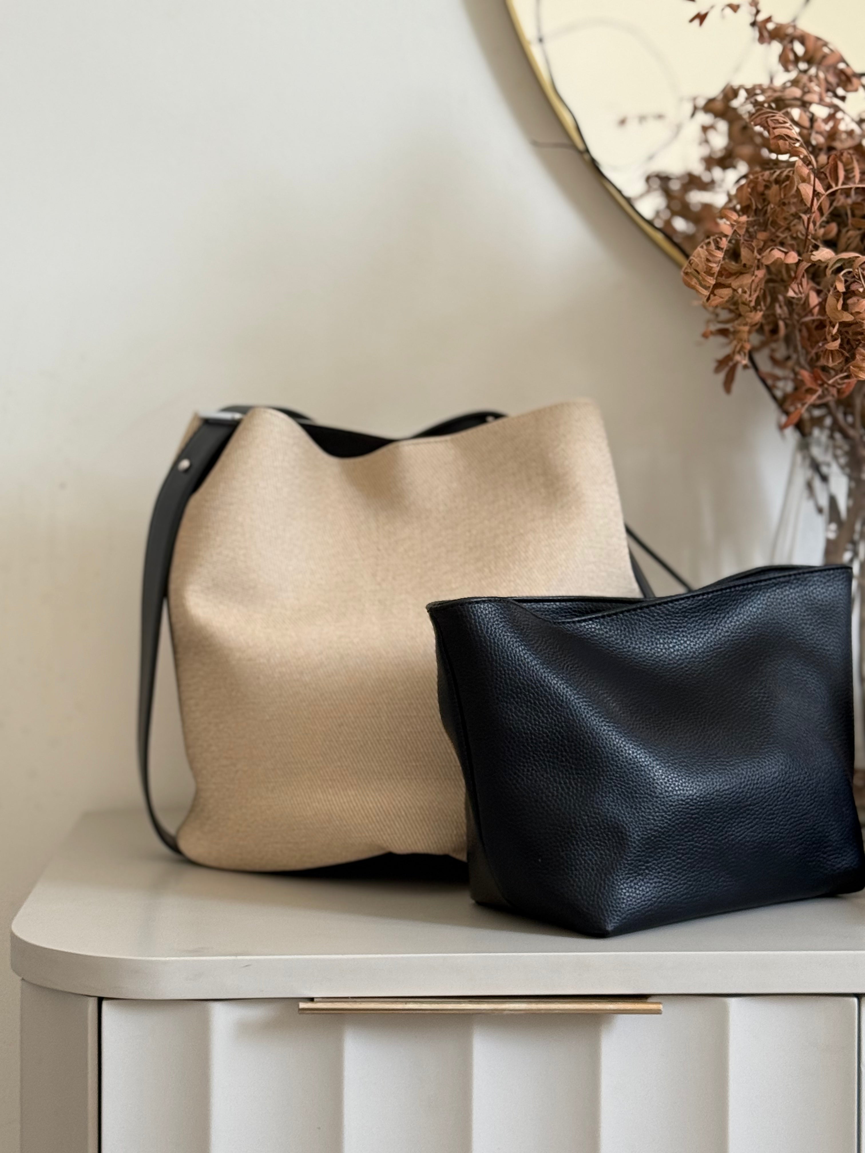 Beige fabric bucket bag with black leather trim.